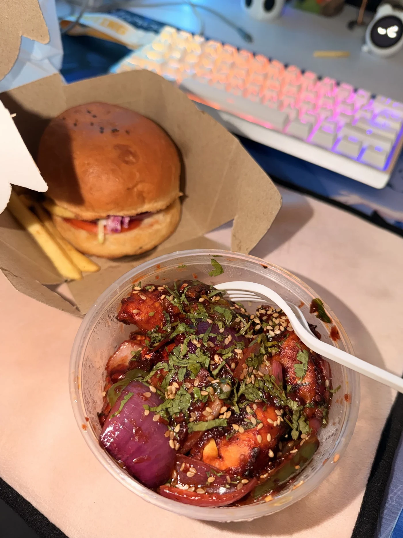 A burger, fries, and a bowl of sauced food in front of a colourful keyboard