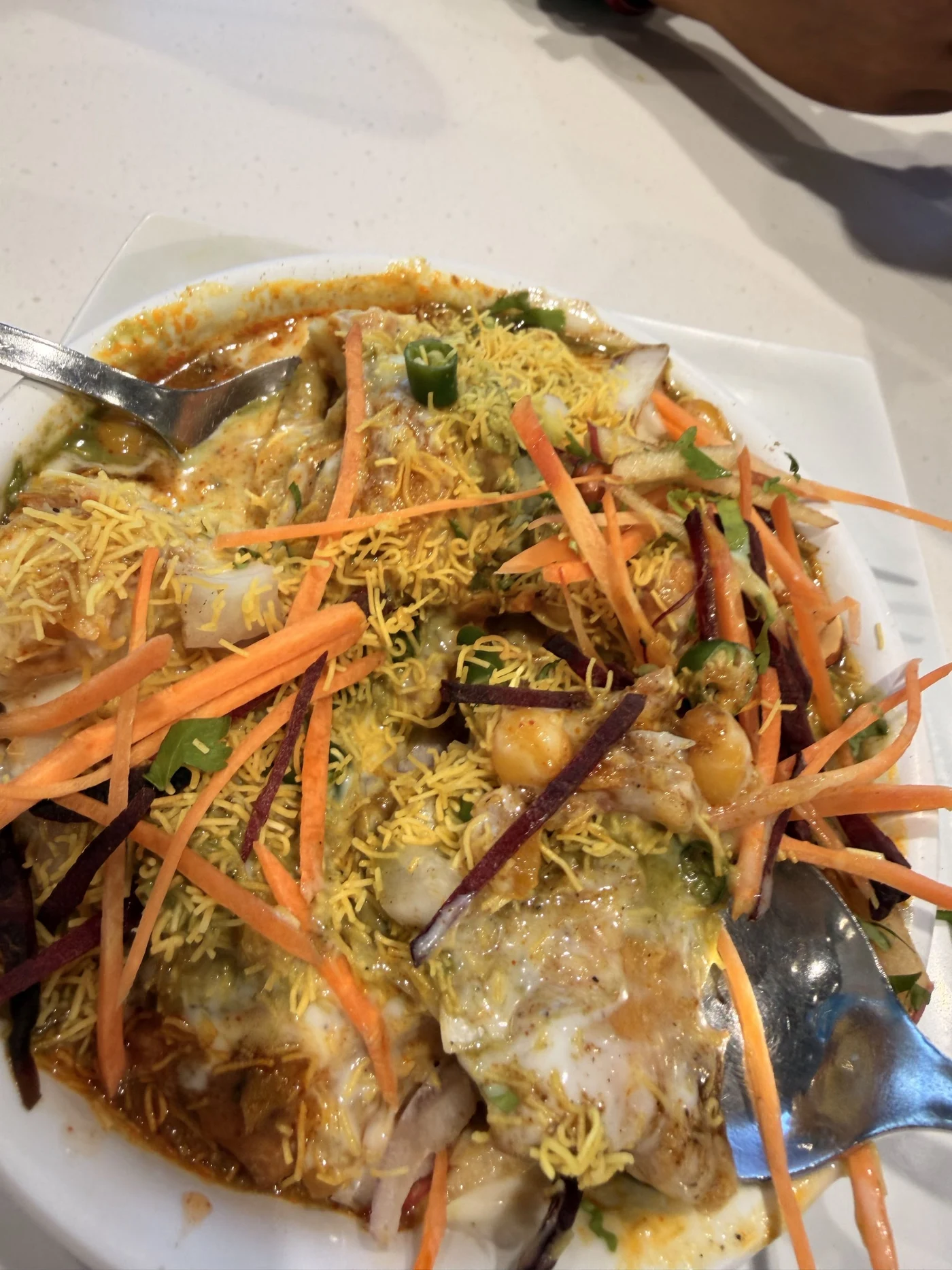A saucy snack plate topped with shredded vegetables and thin crunchy noodles