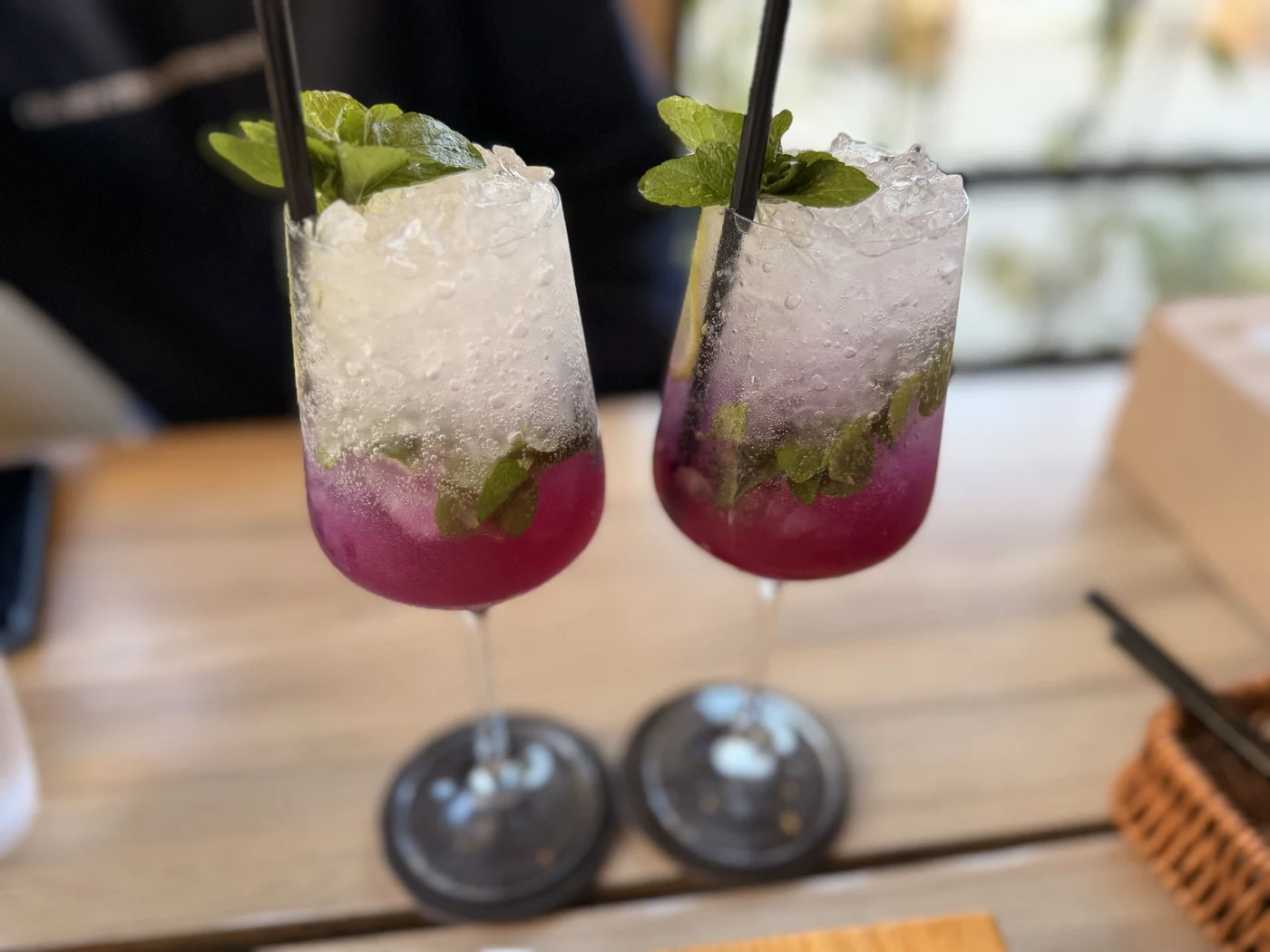 Two iced pink and purple drinks garnished with mint