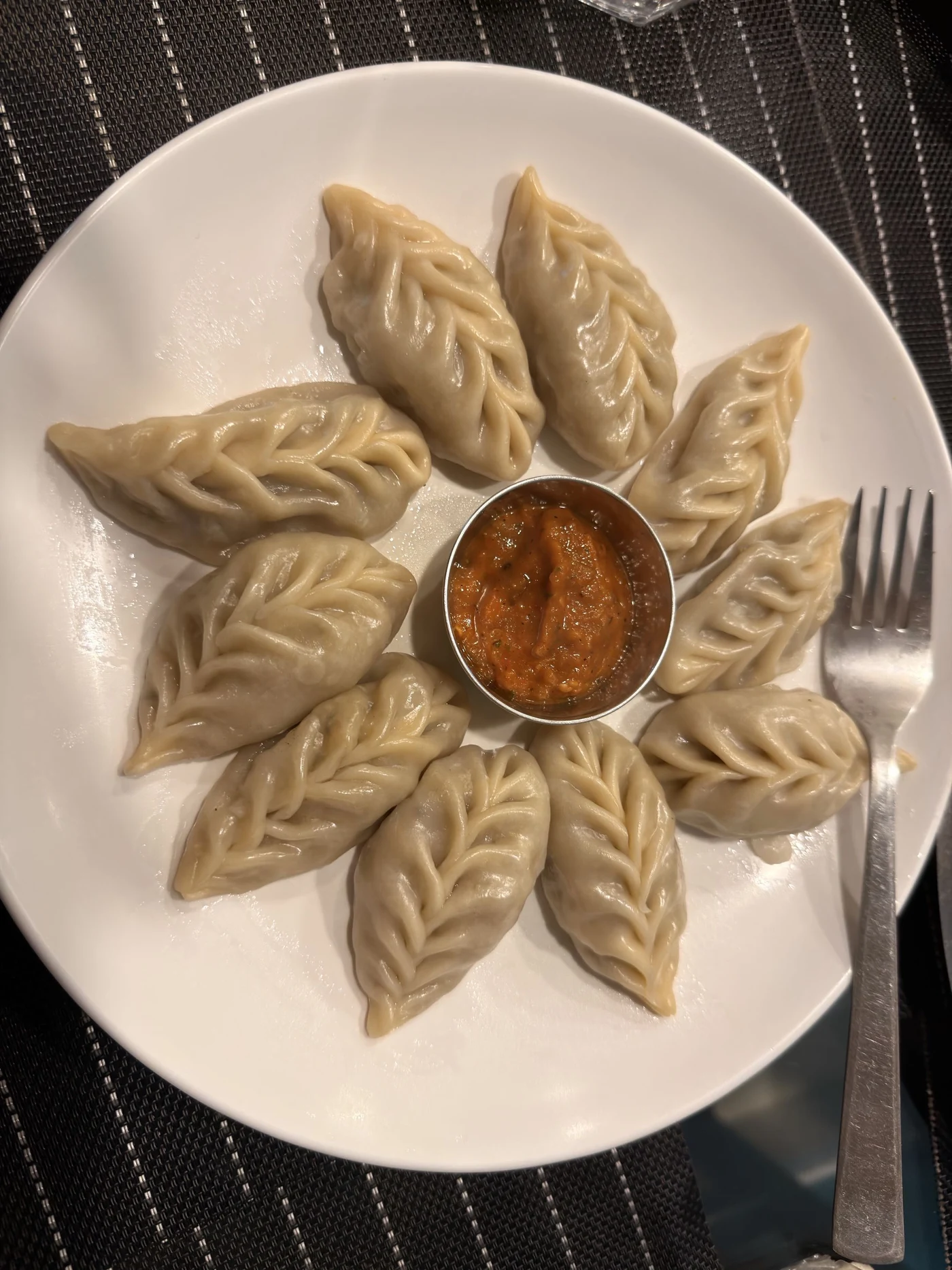 Steamed dumplings arranged in a circle around dipping sauce