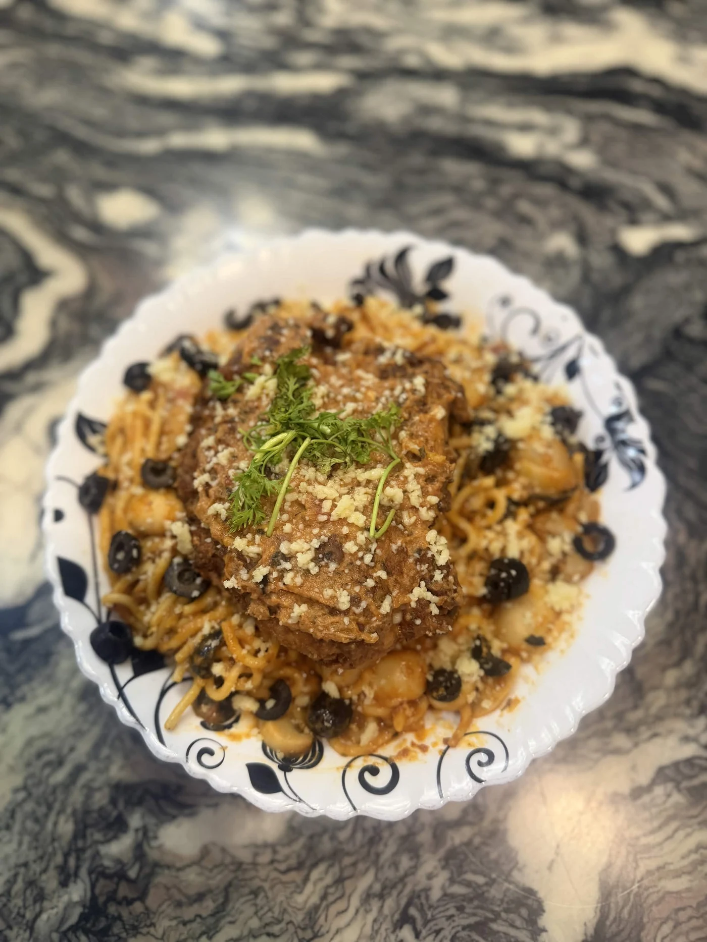 A plate of pasta with mushrooms, olives, grated cheese, and a golden topping