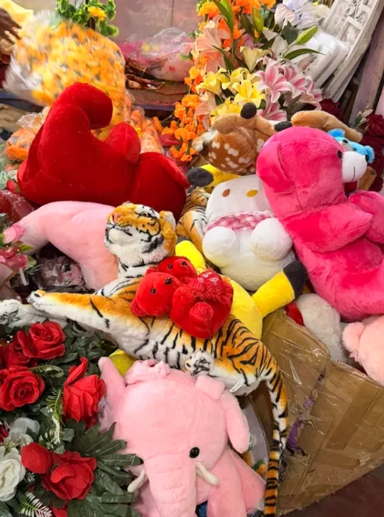Colourful plush animals and bouquets gathered in a shop display