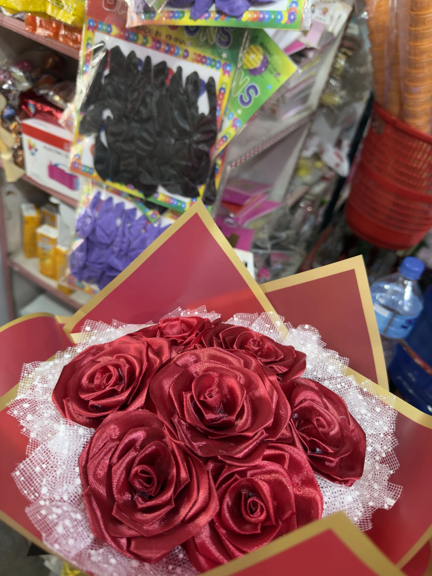 A red bouquet of ribbon roses wrapped in red and gold paper