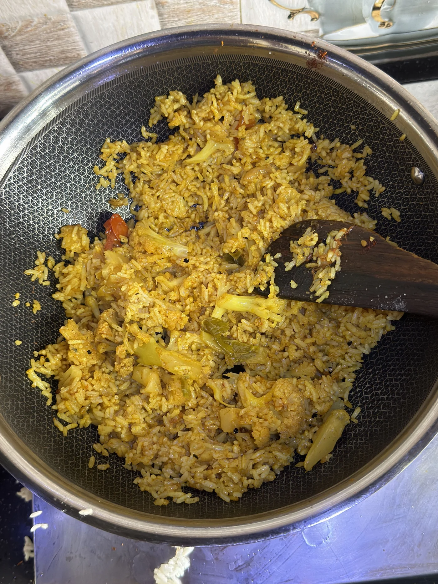 Yellow rice and vegetables in a pan with a wooden spatula