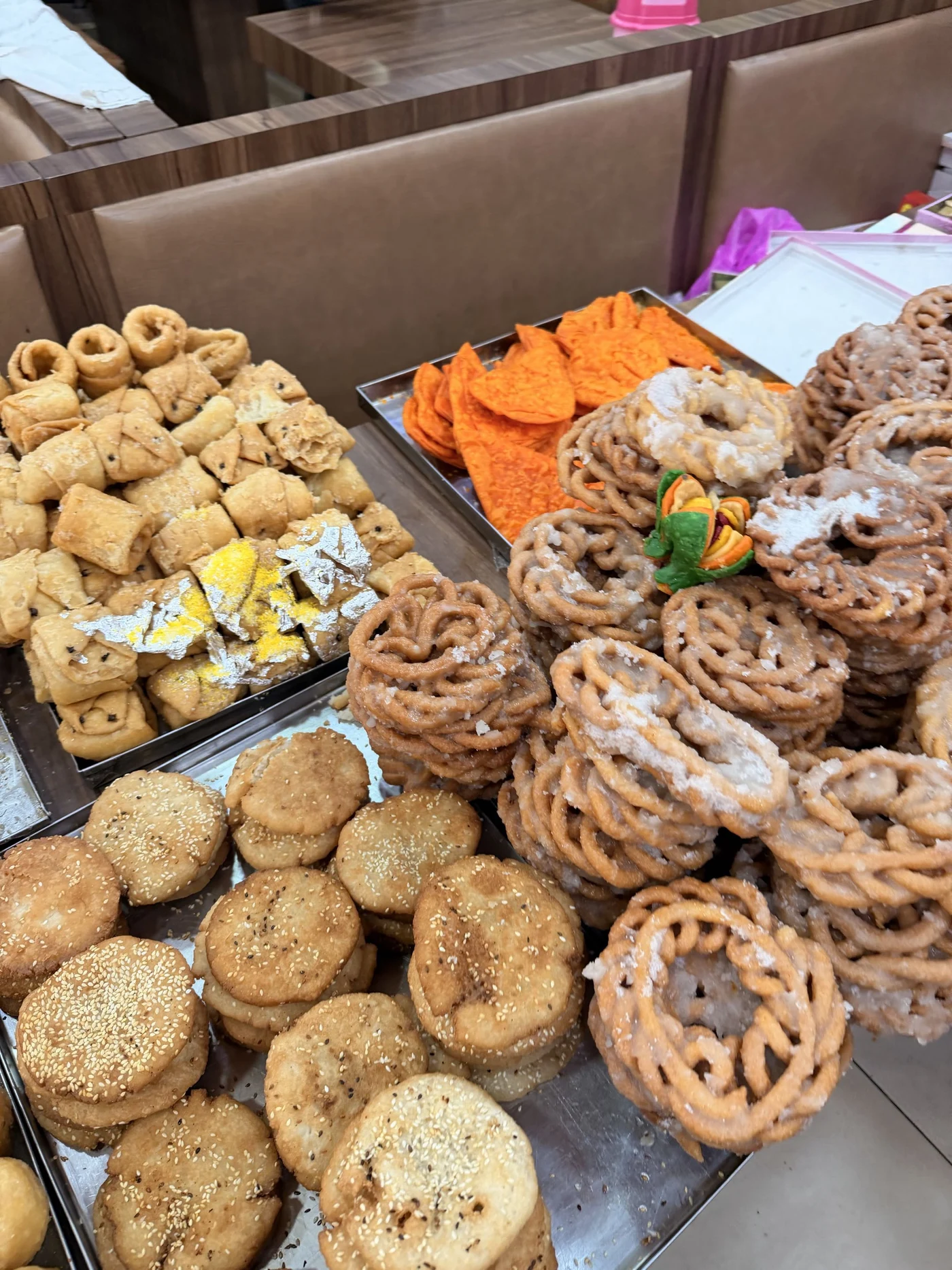 Trays of round biscuits, spiral pastries, and colourful sweets