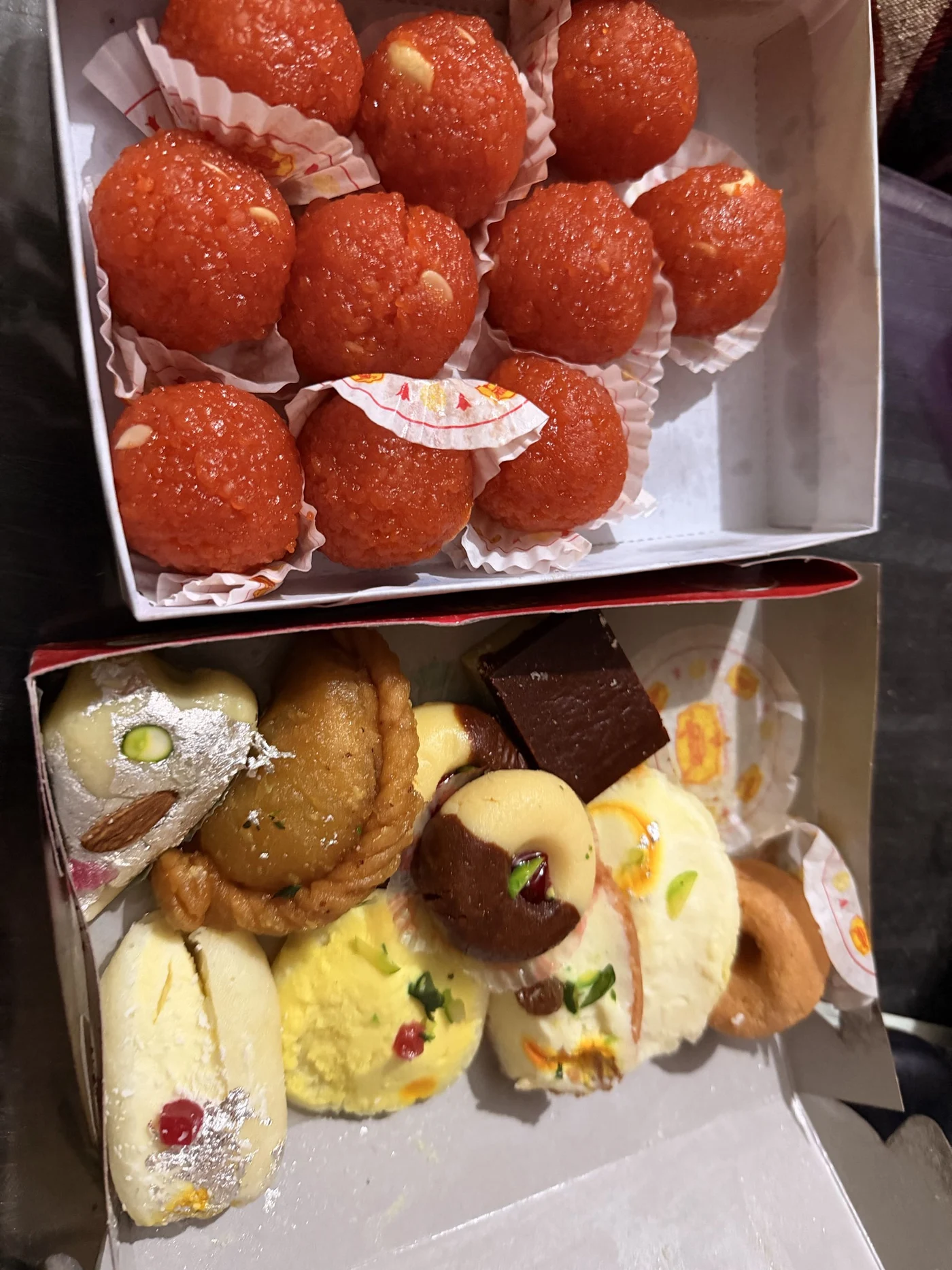 Two boxes of assorted sweets, including orange round sweets and decorated pieces